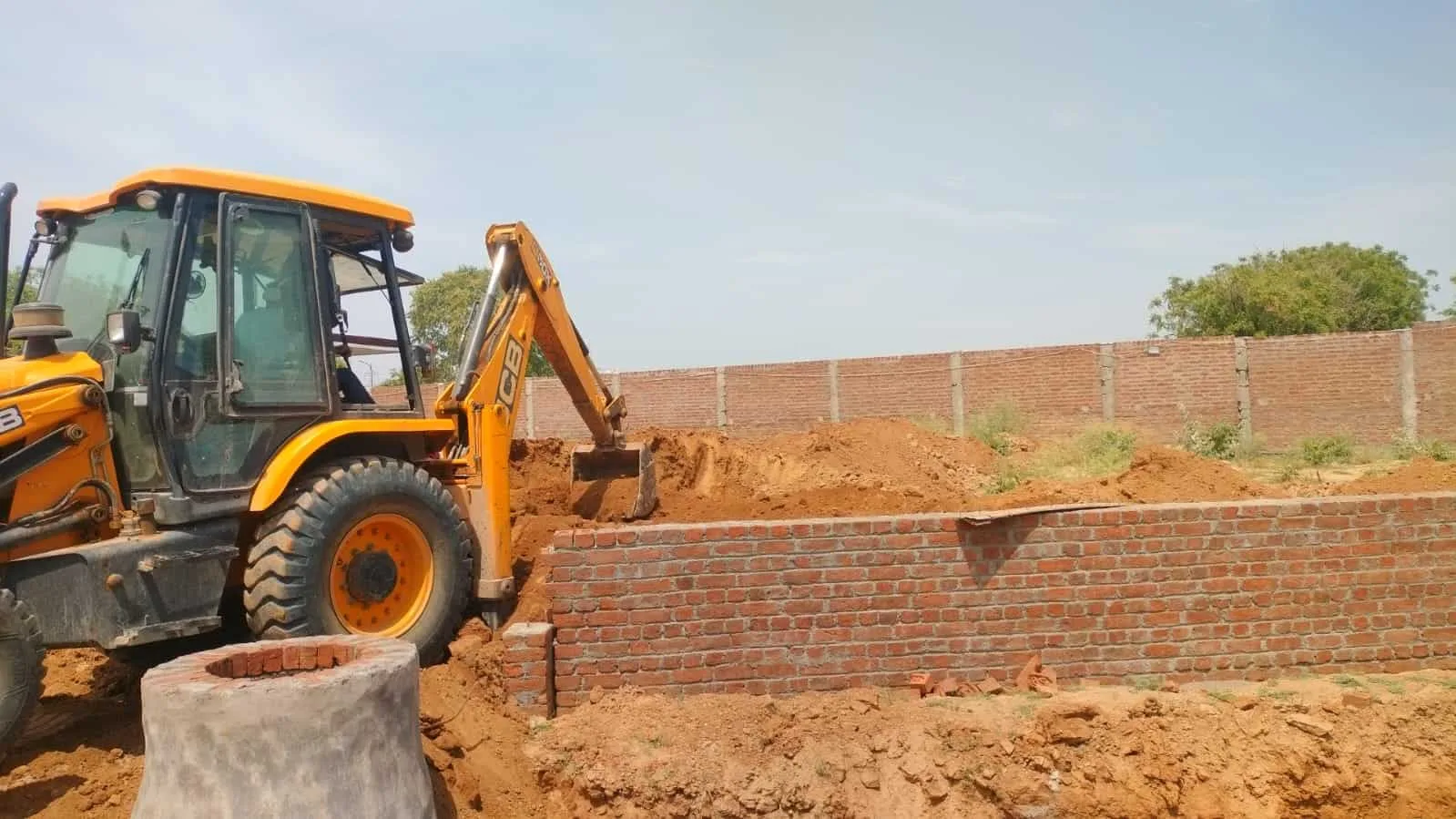 Backhoe loader at Surabhi construction site for building walls and foundations.
